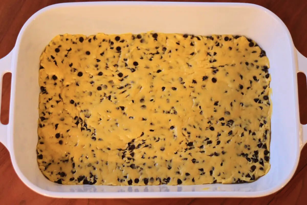 Cake mix chocolate chip cookie bar dough spread in a pan.