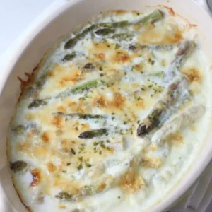 creamed asparagus with parmesan cheese in a white dish.