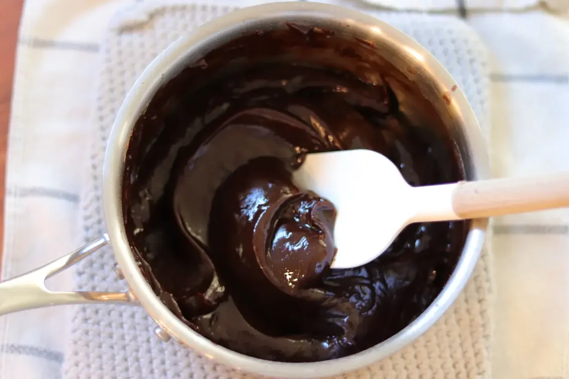 Fudgy brownie frosting in the saucepan after adding the oil and vanilla extract.
