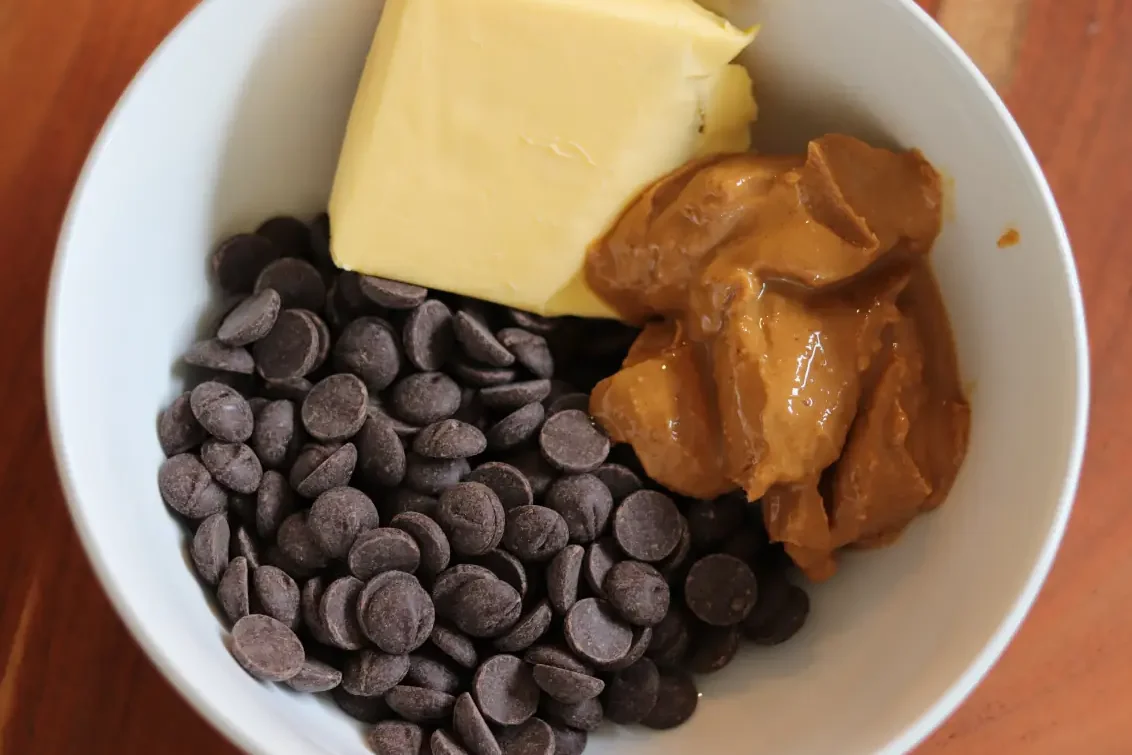 a bowl of chocolate chips, butter, and peanut butter. 