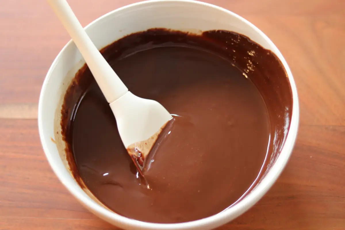 melted chocolate chips, peanut butter, butter, and vanilla, mixed in a bowl. 