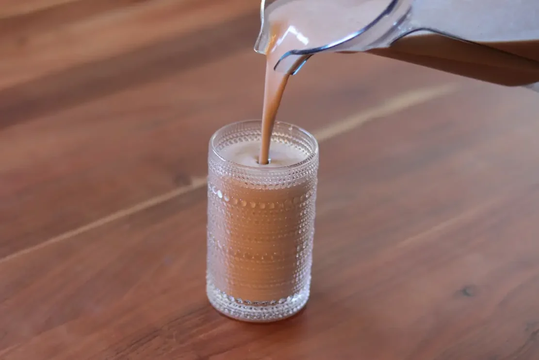 Chocolate milk smoothie being poured into a glass. 