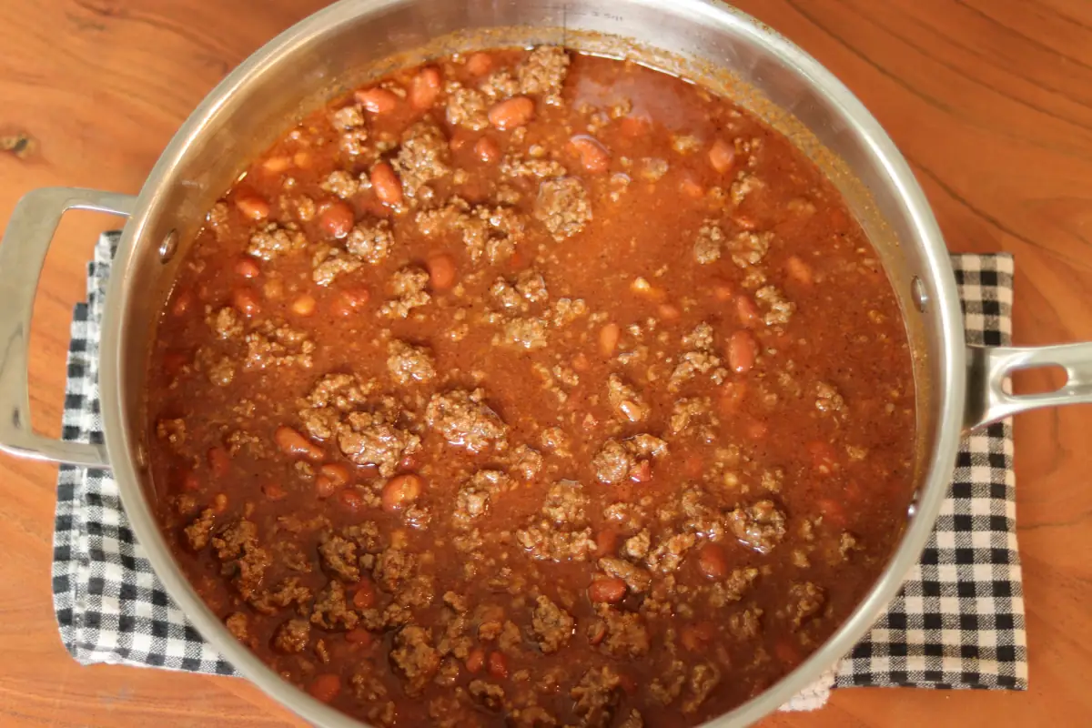Ground beef, tomato juice, beans, and chili seasoning combined in a pan.