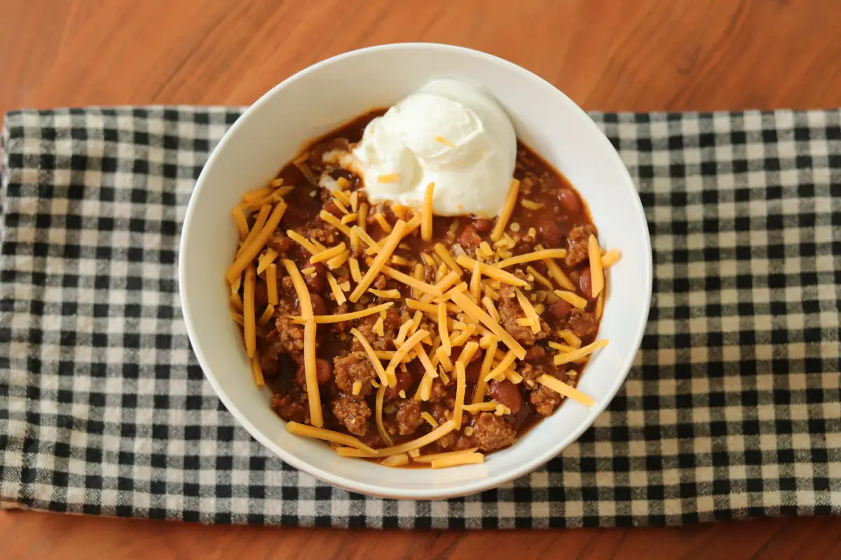 Bowl of 4 ingredient chili with cheddar cheese and sour cream.
