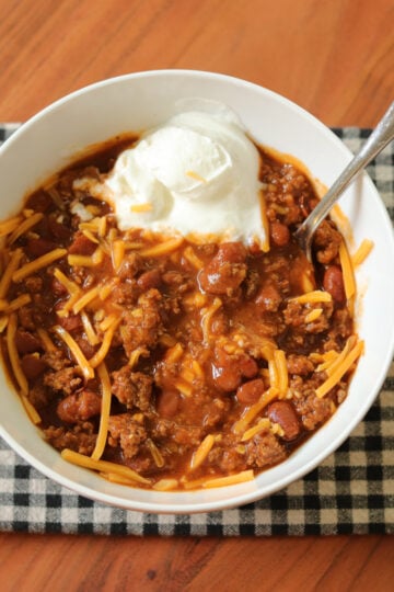 4 ingredient chili served in a bowl with sour cream and cheese.