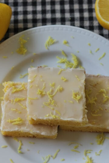 Lemon brownies on a plate topped with lemon zest.