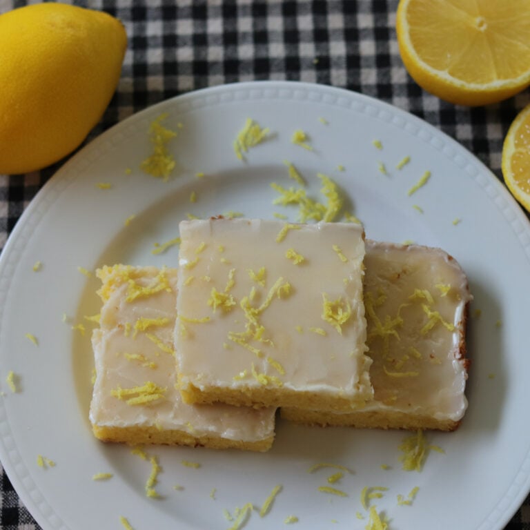 Lemon brownies on a plate topped with lemon zest.
