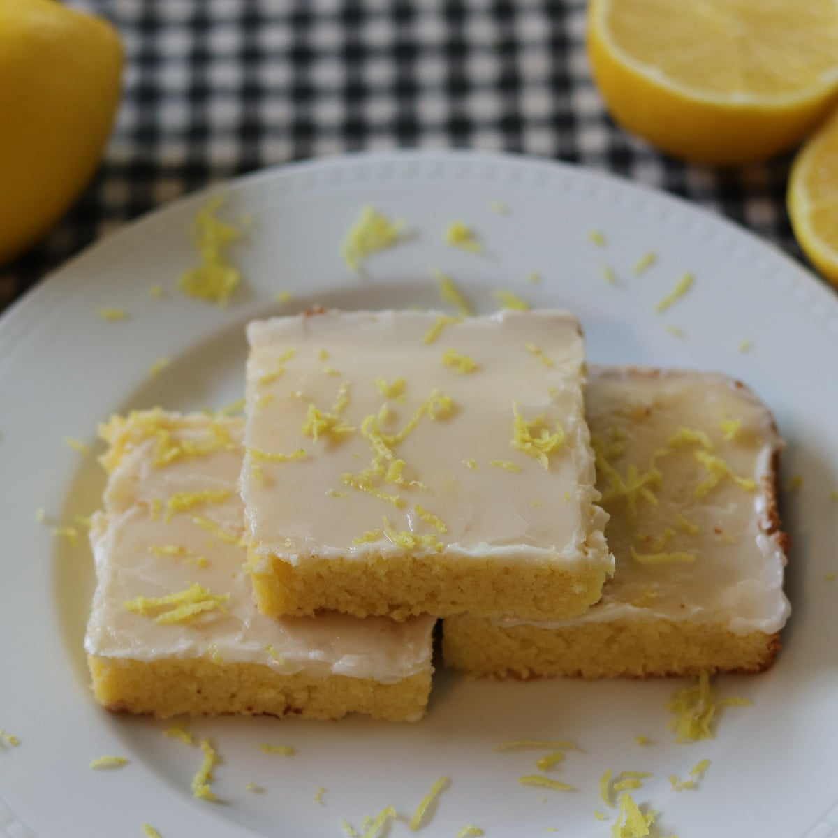 Lemon brownies on a plate topped with lemon zest.