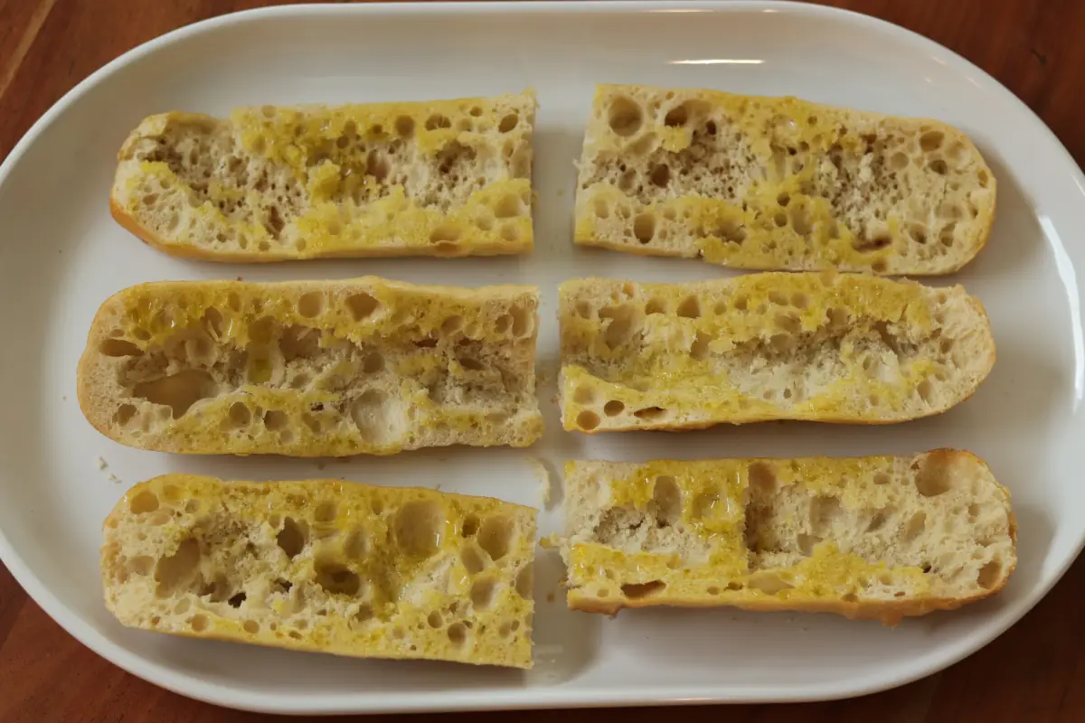 Seasoned french bread on a white platter.