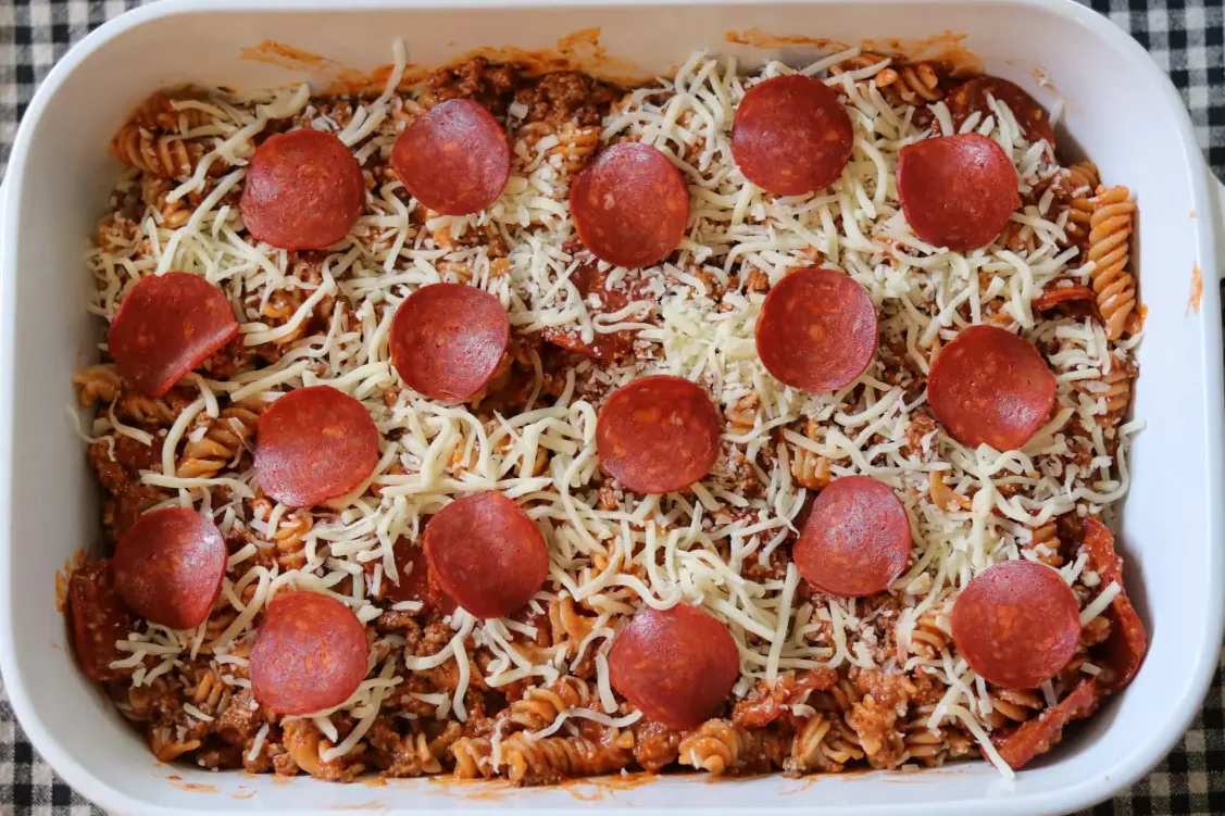 Assembled pizza pasta casserole in a casserole dish.