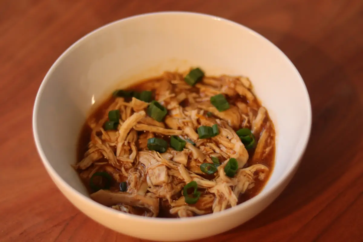 Slow cooker citrus chicken in a bowl garnished with green onion.