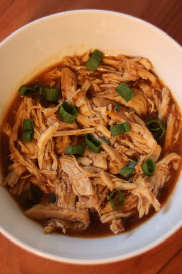 Slow cooker citrus chicken in a bowl garnished with green onions.