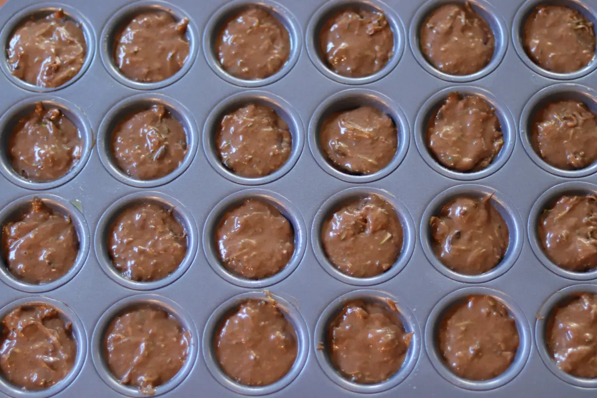 Zucchini mini muffin batter in the muffin tin.