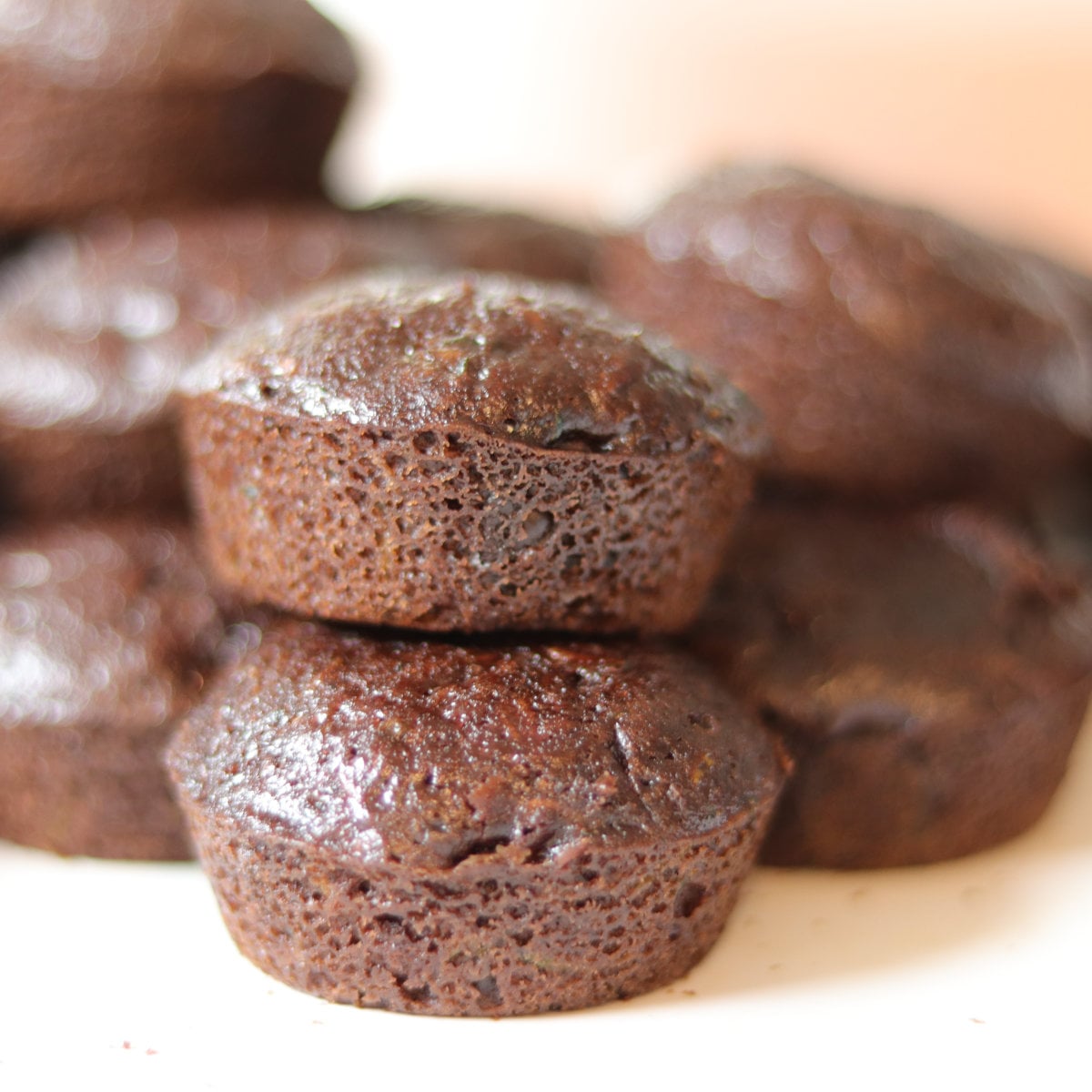 Close up photo of 2 zucchini mini muffins, with muffins behind them.