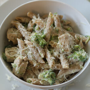 Chicken broccoli alfredo in a bowl topped with parmesan cheese.