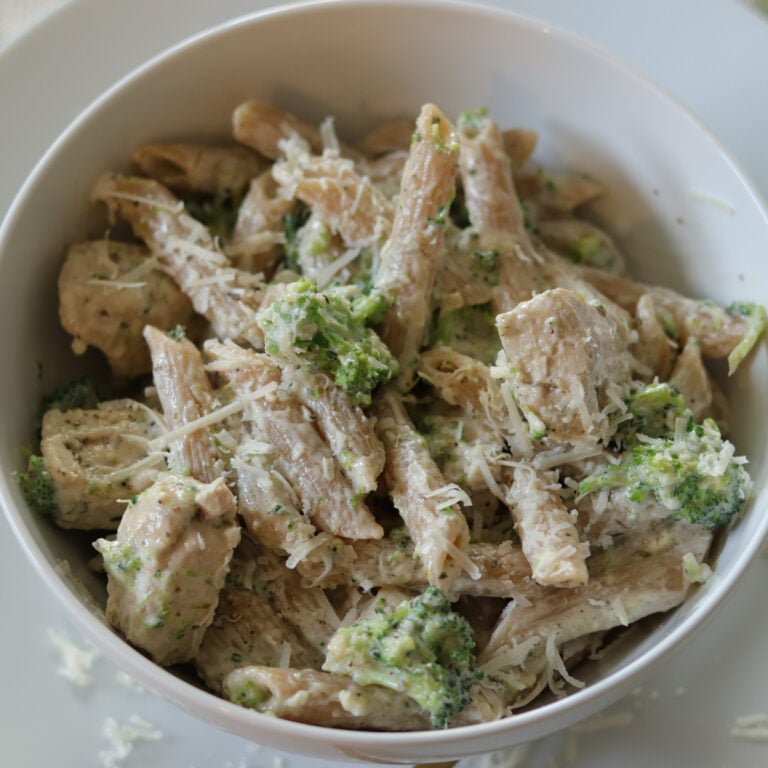 Chicken broccoli alfredo in a bowl topped with parmesan cheese.