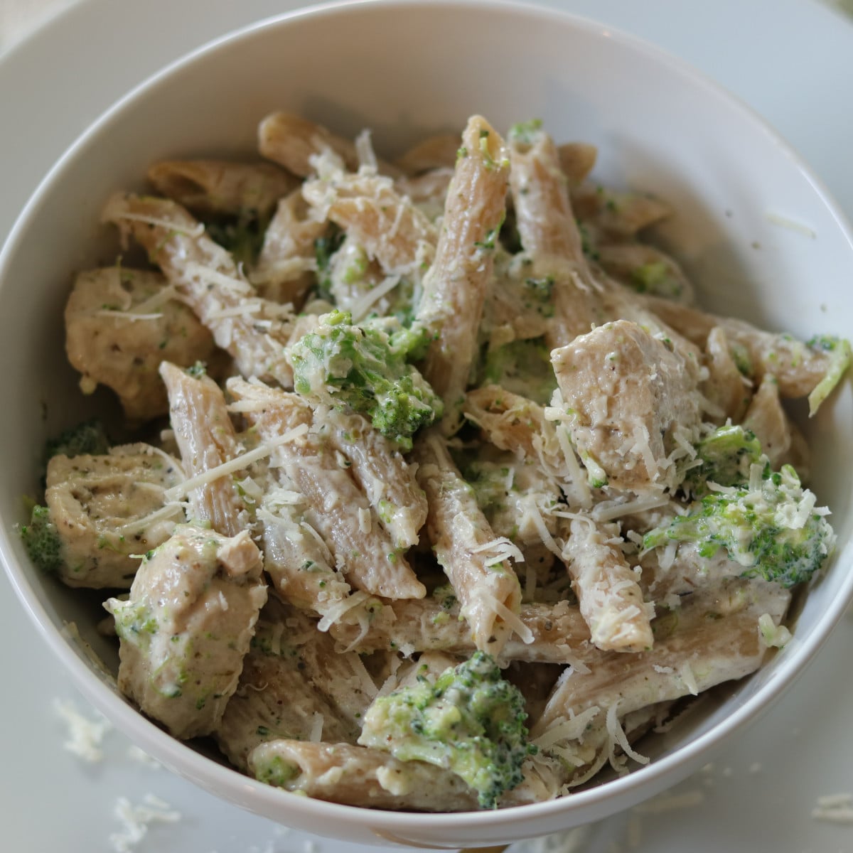 Chicken broccoli alfredo in a bowl topped with parmesan cheese.