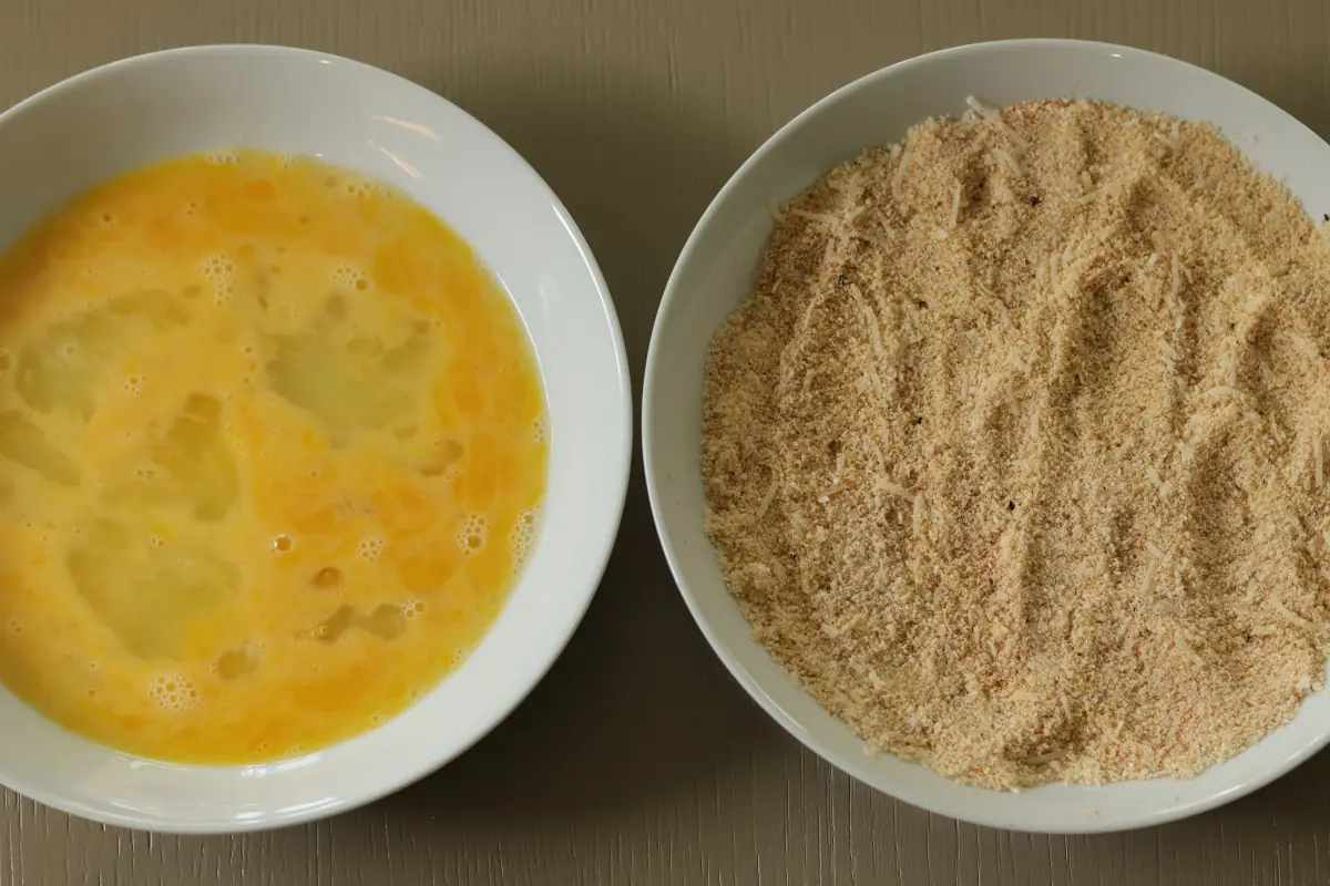 Whisked egg in a bowl, next to an almond flour mixture in a bowl.