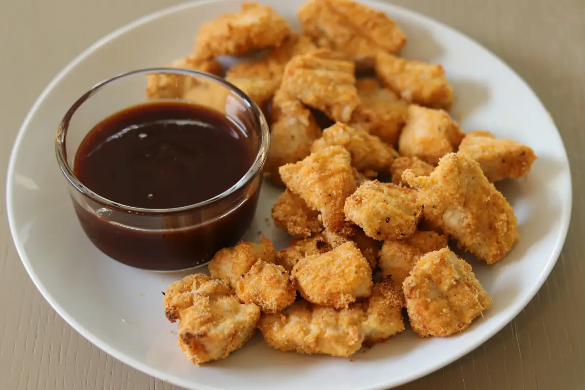 chicken nuggets on a plate with dipping sauce.