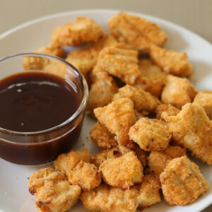 Gluten Free Chicken nuggets on a white plate next to dipping sauce.
