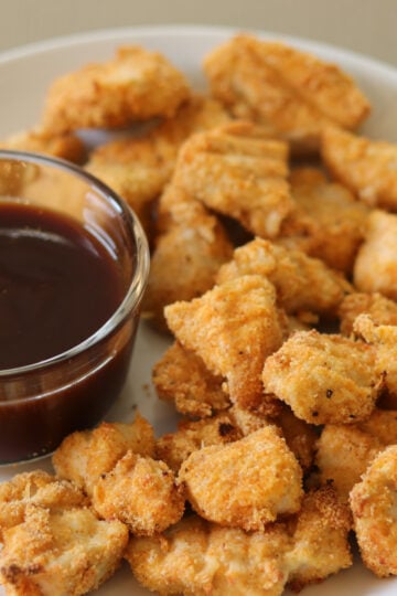 Gluten Free Chicken nuggets on a white plate next to dipping sauce.