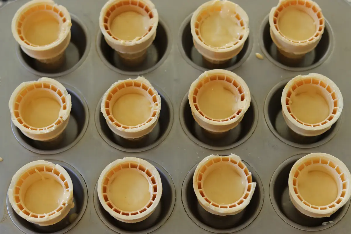 Batter spooned into ice cream cones.