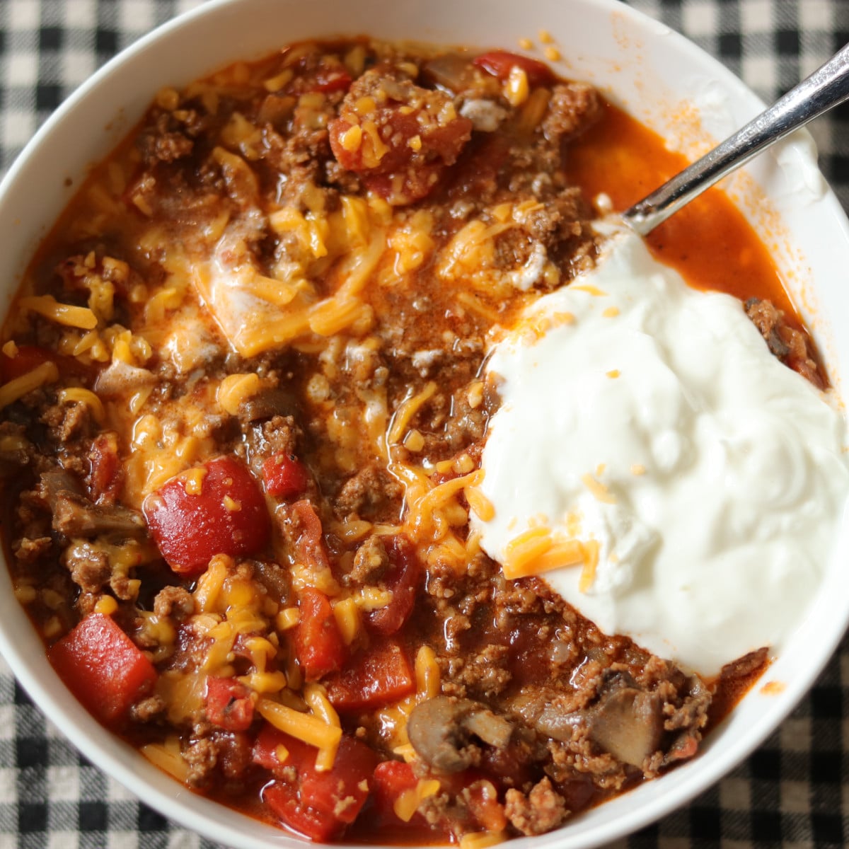 Low carb chili served in a bowl with cheddar cheese and sour cream.