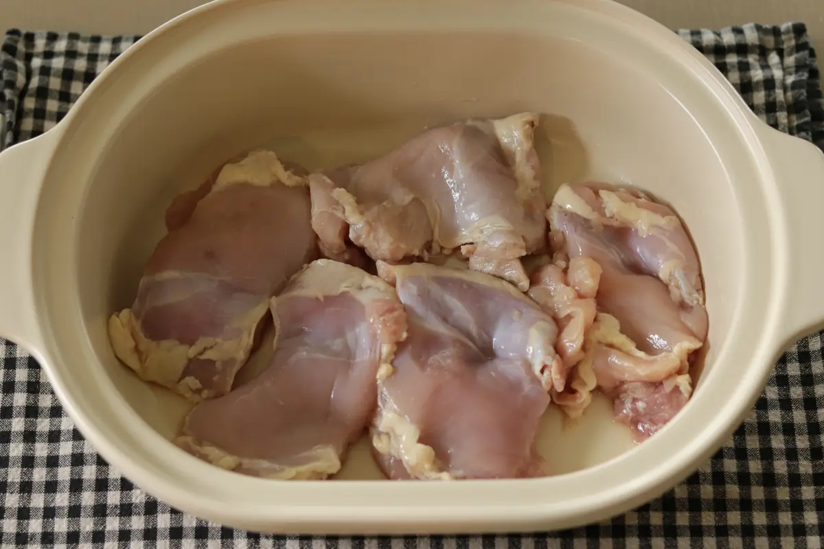 Raw chicken thighs in a slow cooker.