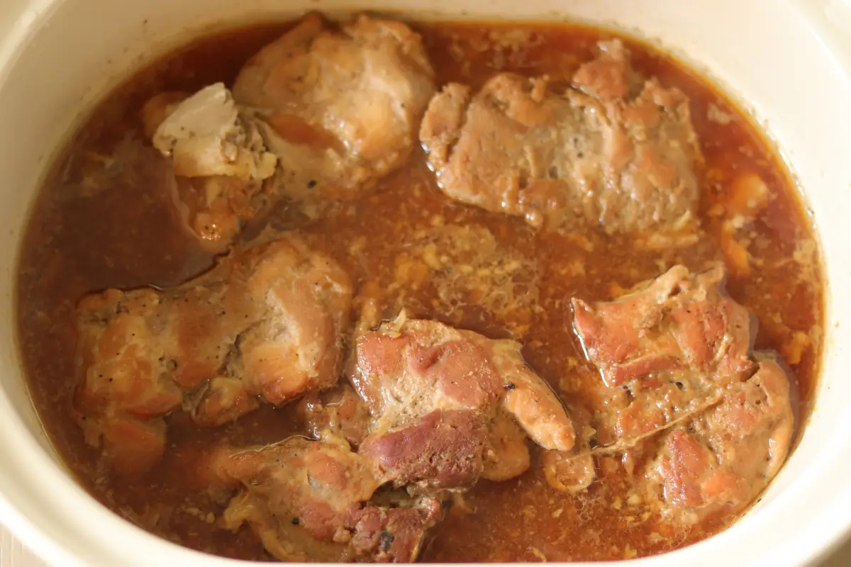 Chicken in the slow cooker that has been cooked in teriyaki sauce.