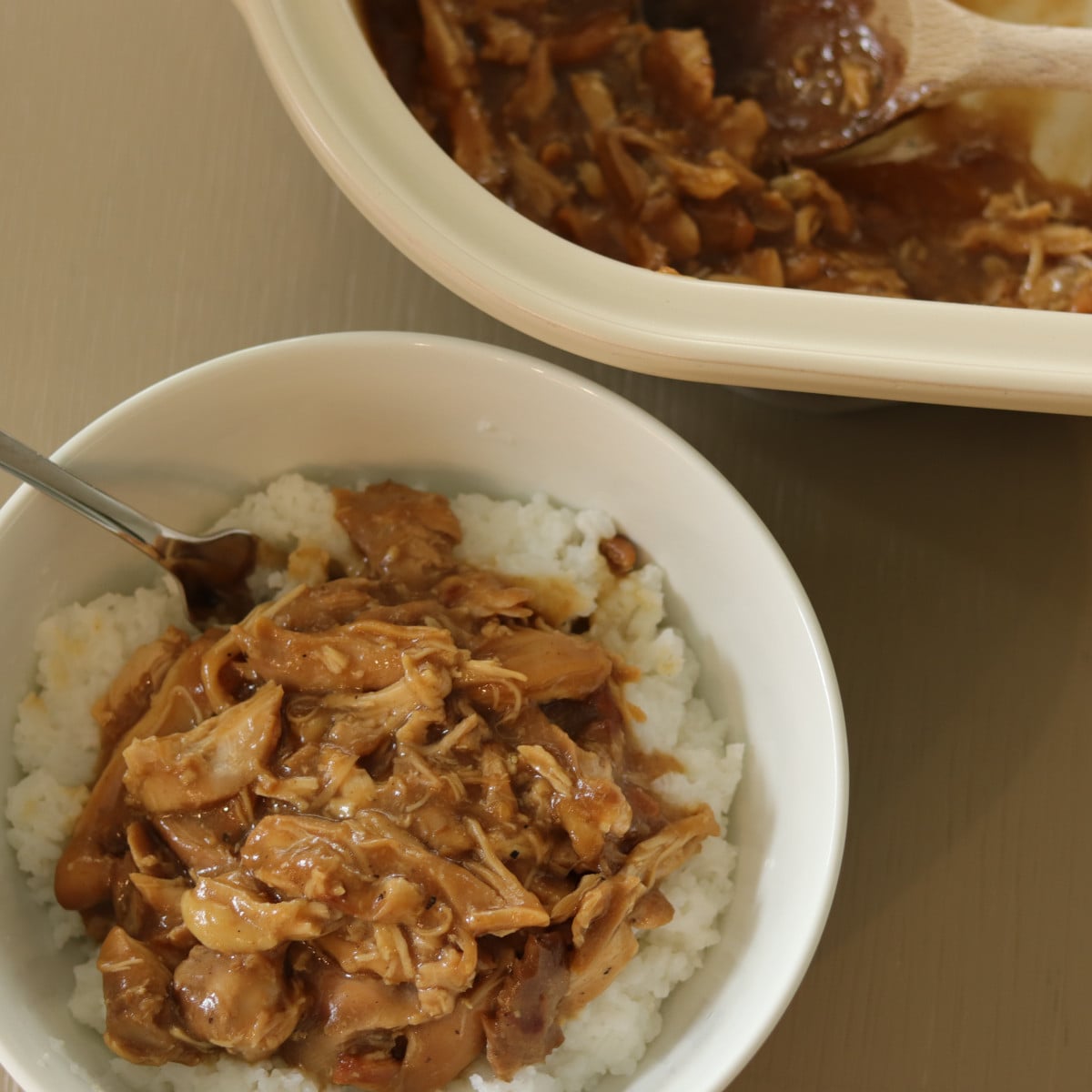 slow cooker chicken teriyaki served in a bowl, with the slow cooker in the background.