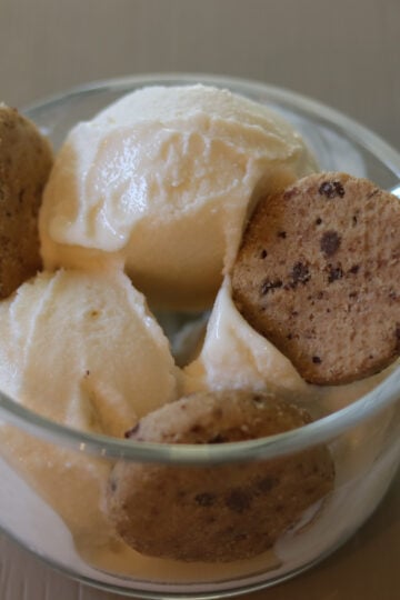 Scoops of ice cream in a bowl with chocolate chip cookies.