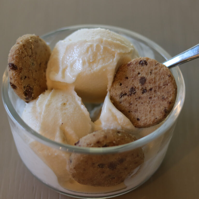 Scoops of ice cream in a bowl with chocolate chip cookies.