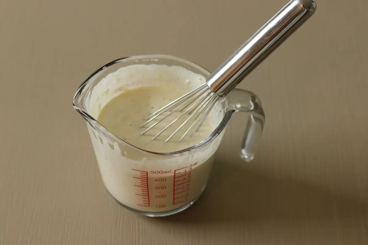 Homemade garlic parmesan dressing in a glass pitcher.