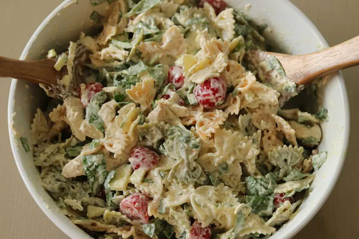 Chicken pasta salad mixed in a bowl with the dressing.