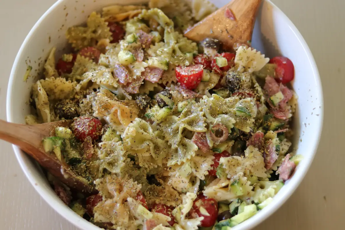 Zesty italian pasta salad mixed with dressing in a white bowl.